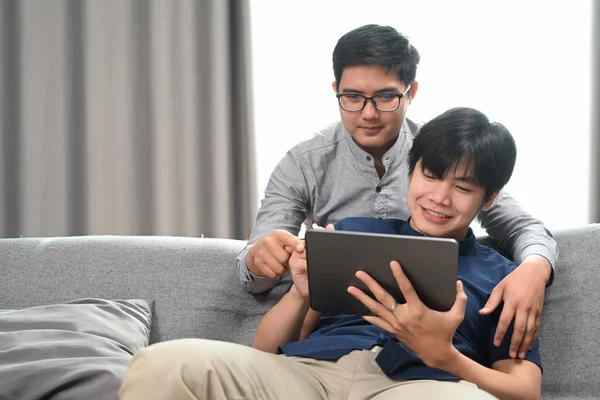 リビングルームで一緒にデジタルタブレットを採用し 使用している同性愛者のカップルの幸せ 同性愛 Lgbtの概念 — ストック写真