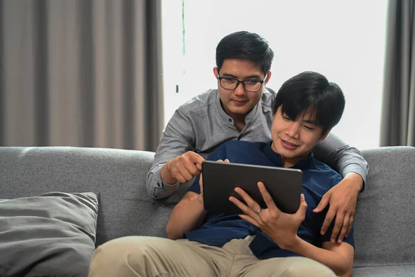 ソファに座っている間 幸せな同性愛者のカップルはデジタルを使用しています 同性愛 Lgbtの概念 — ストック写真
