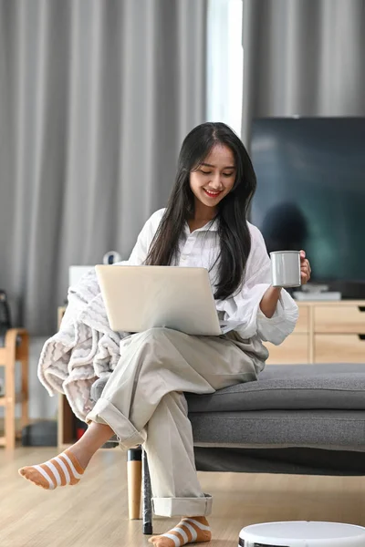 Happy Woman Using Laptop Sofa Robotic Vacuum Cleaner Cleaning Living — Stockfoto