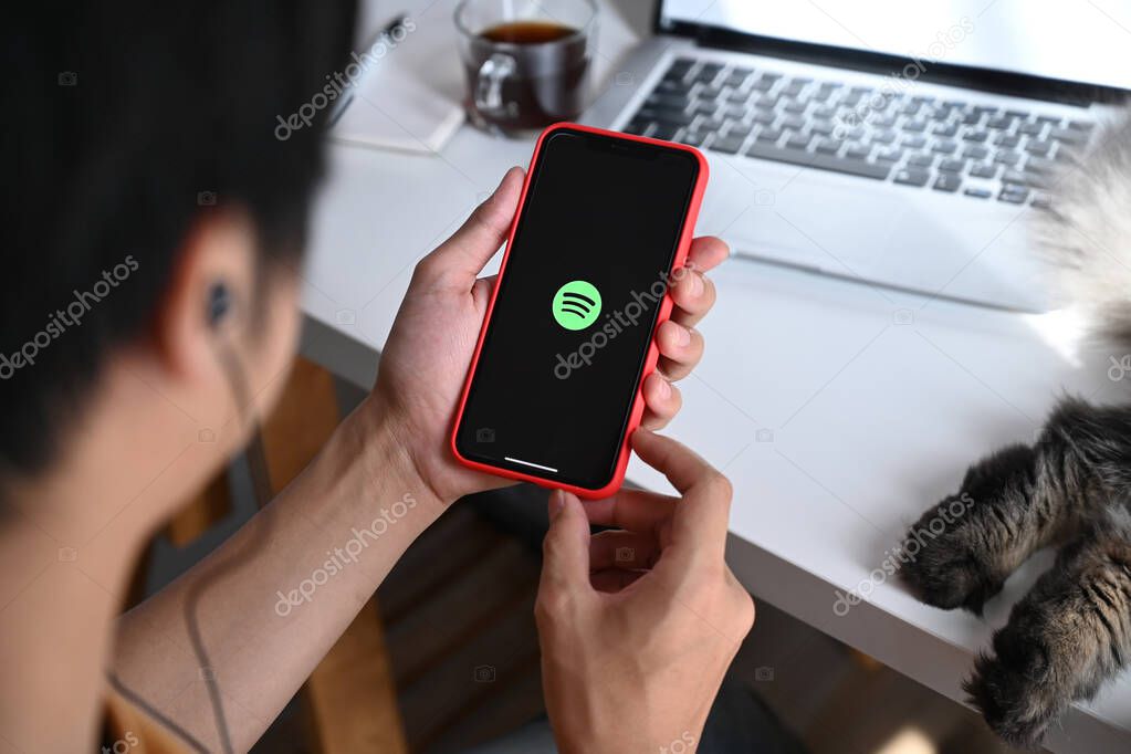 Chiang Mai, Thailand - May 13, 2021 : Man holding iPhone 11 Pro Max with spotify app. Spotify is a music service that offers legal streaming music.