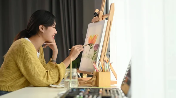 彼女のワークスペースに座っている間 かなり才能のある女性画家は自宅で創造的な絵を描いています — ストック写真