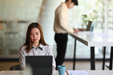 Asyalı çekici iş kadınının ön görüntüsü bilgisayar tableti üzerinde çalışırken aynı zamanda modern ofis odasında oturuyor. .