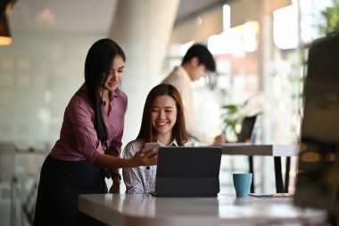 İki güzel bayan mobil uygulama tasarımcısı test ediliyor ve toplantı odasında yeni uygulama özelliklerini tartışıyorlar..