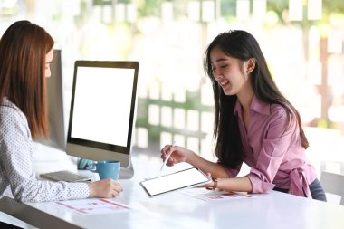 Genç UX tasarımcılarından oluşan küçük bir ekip ofis odasında dijital tabletle birlikte çalışıyor..