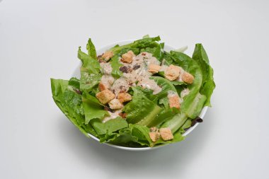 Salata, marul, pastırma ve kızarmış ekmekleri beyaz masada bir kasede.. 