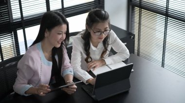 Kendine güvenen iki iş adamı, ofiste tablet kullanıyor ve tartışıyorlar..