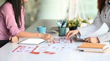 ux tasarımcılarının kırpılmış görüntüleri masadaki yerleşim planlarıyla mobil web sitesinin arayüzünü planlıyorlar.