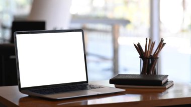 Boş ekranı, kırtasiyesi ve not defterleri olan bir tablet bilgisayarın ahşap masadaki görüntüsü.