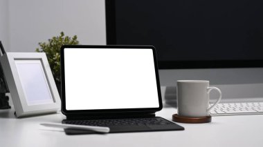Boş ekran tableti, kahve fincanı ve çerçeveli beyaz masa üzerinde modern iş yeri.