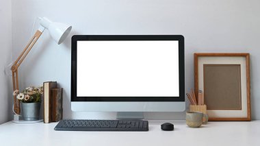Boş bilgisayar ve beyaz masa üzerinde çeşitli ofis araçları ile modern çalışma alanının ön görünümü.