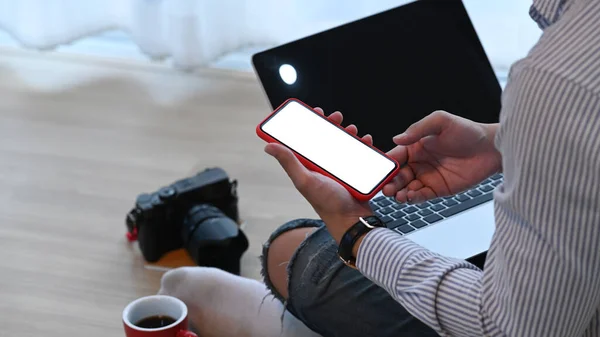拍照的摄影师或设计师坐在笔记本电脑前的地板上 用的是智能手机 — 图库照片