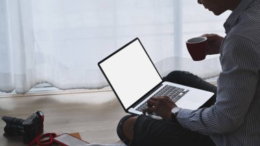 Serbest fotoğrafçı, iş yerinde kahve içerken dizüstü bilgisayarla çalışıyor..