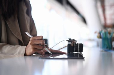 Dijital tablet üzerinde çalışan genç bayan fotoğrafçı ya da tasarımcının yakın görüntüsü.