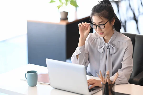 オフィスのコンピュータのラップトップで働く眼鏡の思考のビジネス女性 — ストック写真