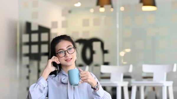 Jovem Funcionária Conversando Celular Segurando Xícara Café Enquanto Estava Sentado — Fotografia de Stock
