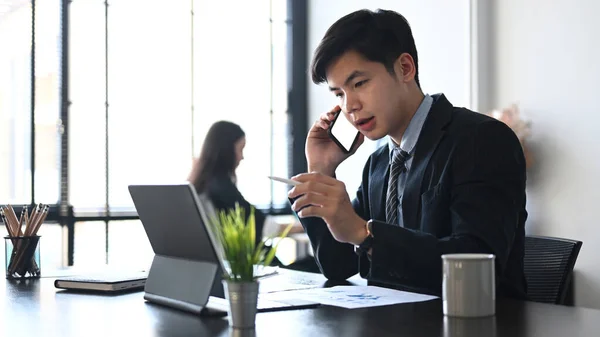 Biznesmen Garniturze Rozmawia Przez Telefon Komórkowy Pracuje Tabletem Siedząc Biurze — Zdjęcie stockowe