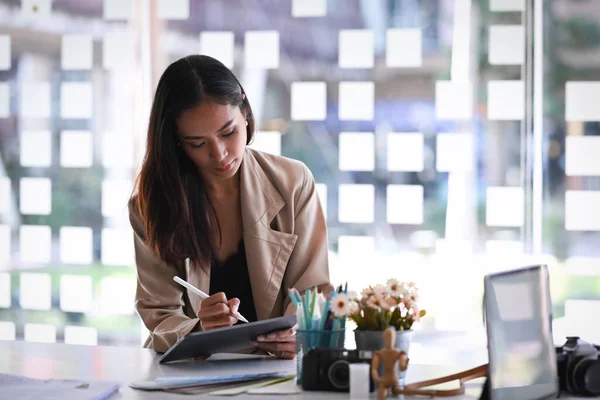 A businesswoman working and analyzing business statistics with computer tablet at her office desk.