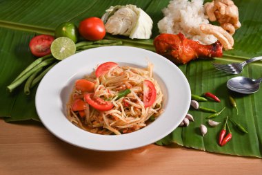 Yeşil papaya salatası ya da ızgara tavuklu Som Tum ve ahşap masada yapışkan pirinç..