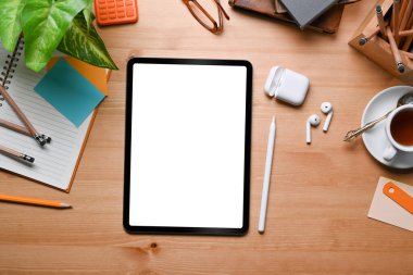 Üst görünüm dijital tablet, stilus kalem, kulaklık, defter ve kırtasiye malzemelerini ahşap masa üzerinde oluşturur..