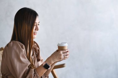 Elinde bir fincan kahveyle gülümseyen genç bir kadın..