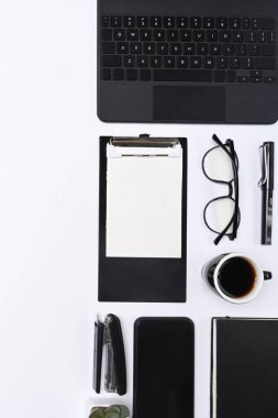 Cep telefonu, dosya, bardaklar, kahve fincanı ve klavye beyaz arka planda..