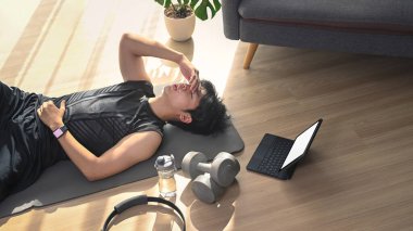 Oturma odasındaki egzersizlerden sonra paspasın üzerinde yatan yorgun genç adam..