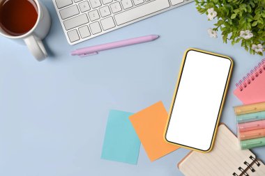 Akıllı telefon, yapışkan not, kahve fincanı ve mavi arka plandaki defter..