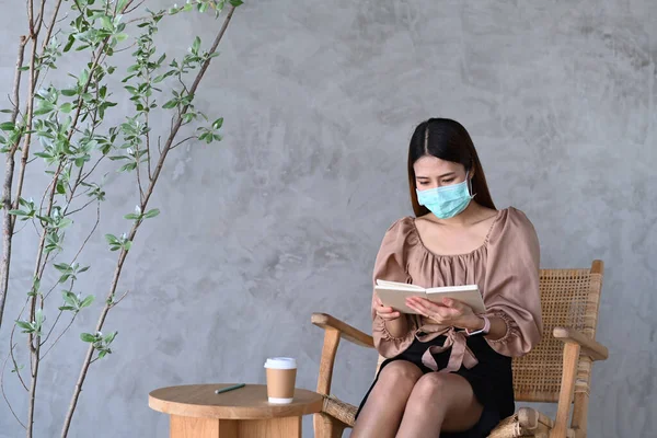 Jonge Aziatische Vrouw Beschermende Masker Zitten Cafe Lezen Boek — Stockfoto