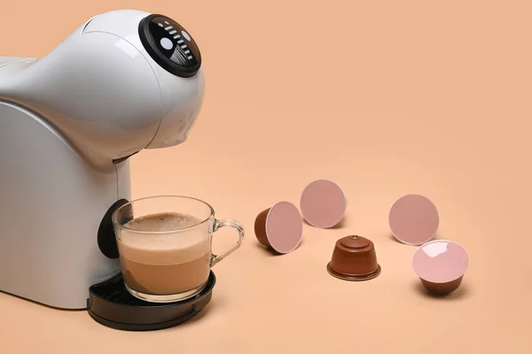 Coffee machine with cup and coffee capsules.