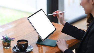 İş kadını elinde stilus kalemle dijital tablet ekranını işaret ediyor.