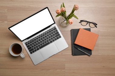 Ahşap arka planda dizüstü bilgisayar, defter ve kahve fincanı..