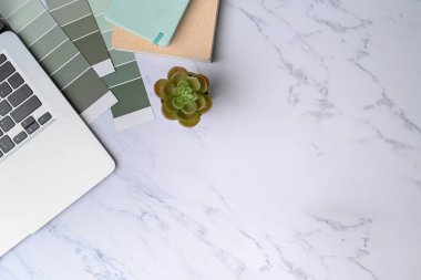 Dizüstü bilgisayarı, renk örneği ve mermer arka planda not defteri olan en az çalışma alanı.