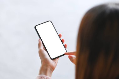 Genç bir kadın açık havada otururken beyaz yeşille akıllı telefonları taklit ediyor..