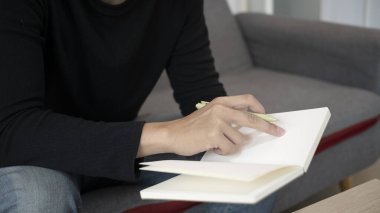 Kanepede oturup kitap okuyan bir adam..