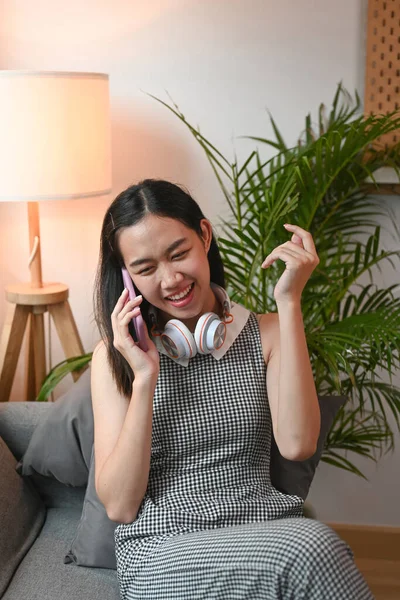 Szczęśliwa Młoda Kobieta Rozmawia Przez Telefon Komórkowy Przyjaciółmi Siedząc Kanapie — Zdjęcie stockowe