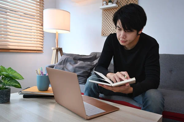 Jong Aziatische Man Holding Notebook Met Behulp Van Laptop Terwijl — Stockfoto