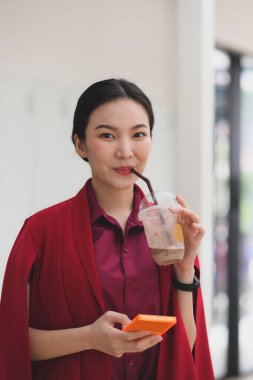 Çekici kadın buzlu kahve içiyor ve cep telefonu kullanıyor..