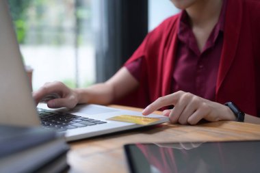 Tahta masadaki bilgisayarla internetten alışveriş yapan bir kadın..