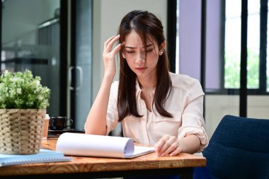 Ofis masasında ciddi bir kadın ofis çalışanı rapor okuyor..