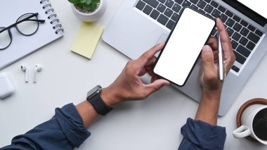 Beyaz ofis masasında akıllı telefon kullanan tepeden bakan adam..