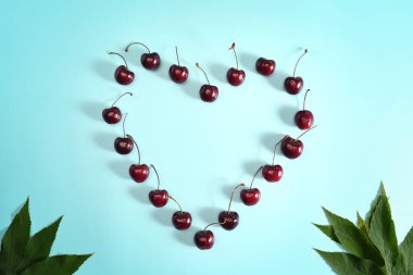 Mavi arka planda yaprakları olan taze kirazlar.