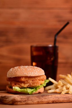 Lezzetli ev yapımı hamburger, kızarmış patates ve ahşap masada meşrubat..