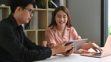 İş adamları toplantı odasında dijital tablet hakkında tartışıyor ve bilgi paylaşıyorlar.