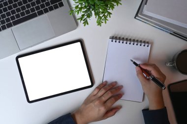 Yukarıdaki adam not defterine not alıyor ve rakam tableti kullanıyor.