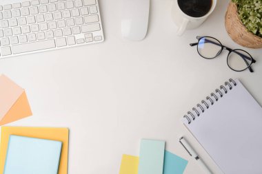 Not defteri, yapışkan notlar ve kahve fincanı olan beyaz ofis masası..