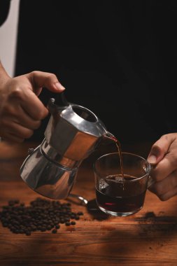 Yakından kahve dolduran adam bir fincana kahve dolduruyor..