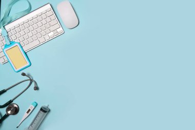 Stetoskop, klavye ve mavi arka planda boş rozet. Doktor çalışma alanı.