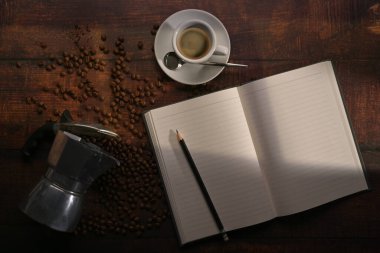 Görüntü defterinin üstünde, Moka demliği ve rustik ahşap arka planda kavrulmuş kahve çekirdekleri..