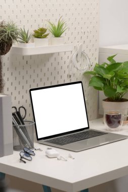 Dizüstü bilgisayarı ve ev bitkisi olan rahat bir iş yeri.