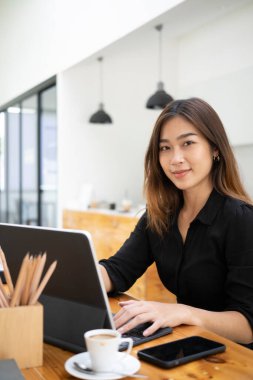 Güzel bir iş kadını bilgisayar tabletiyle çalışıyor ve kameraya bakıyor..